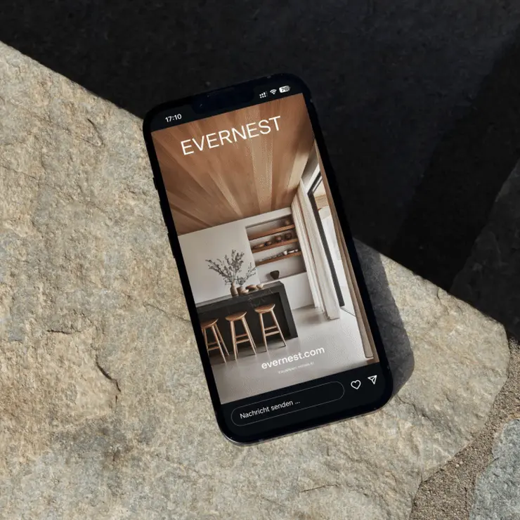 Smartphone zeigt eine moderne Wohnküche mit Holzdecke, Kücheninsel und Barhockern.