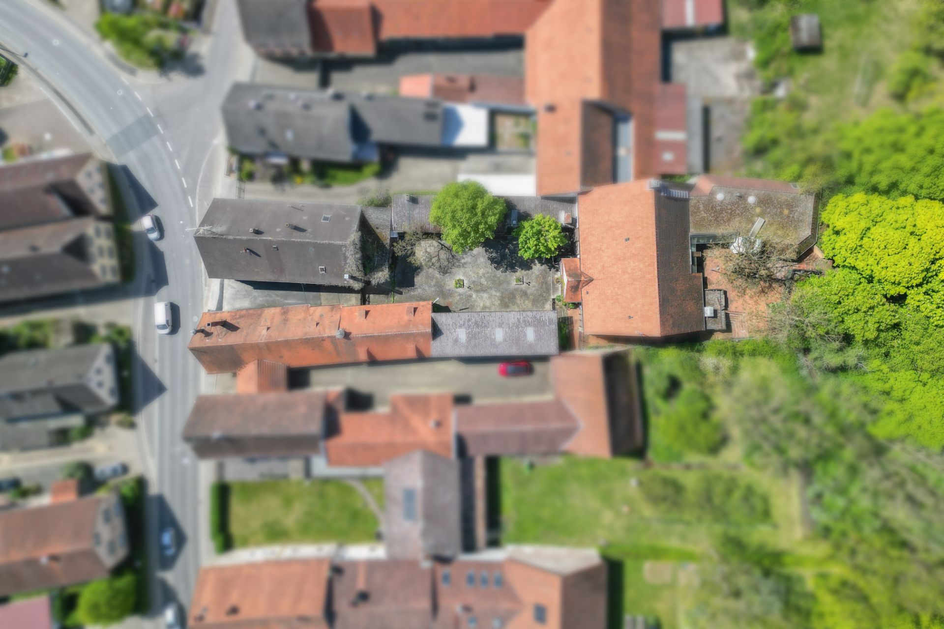 Luftaufnahme mehrerer Wohnhäuser mit Innenhof und umgebenden Gärten.