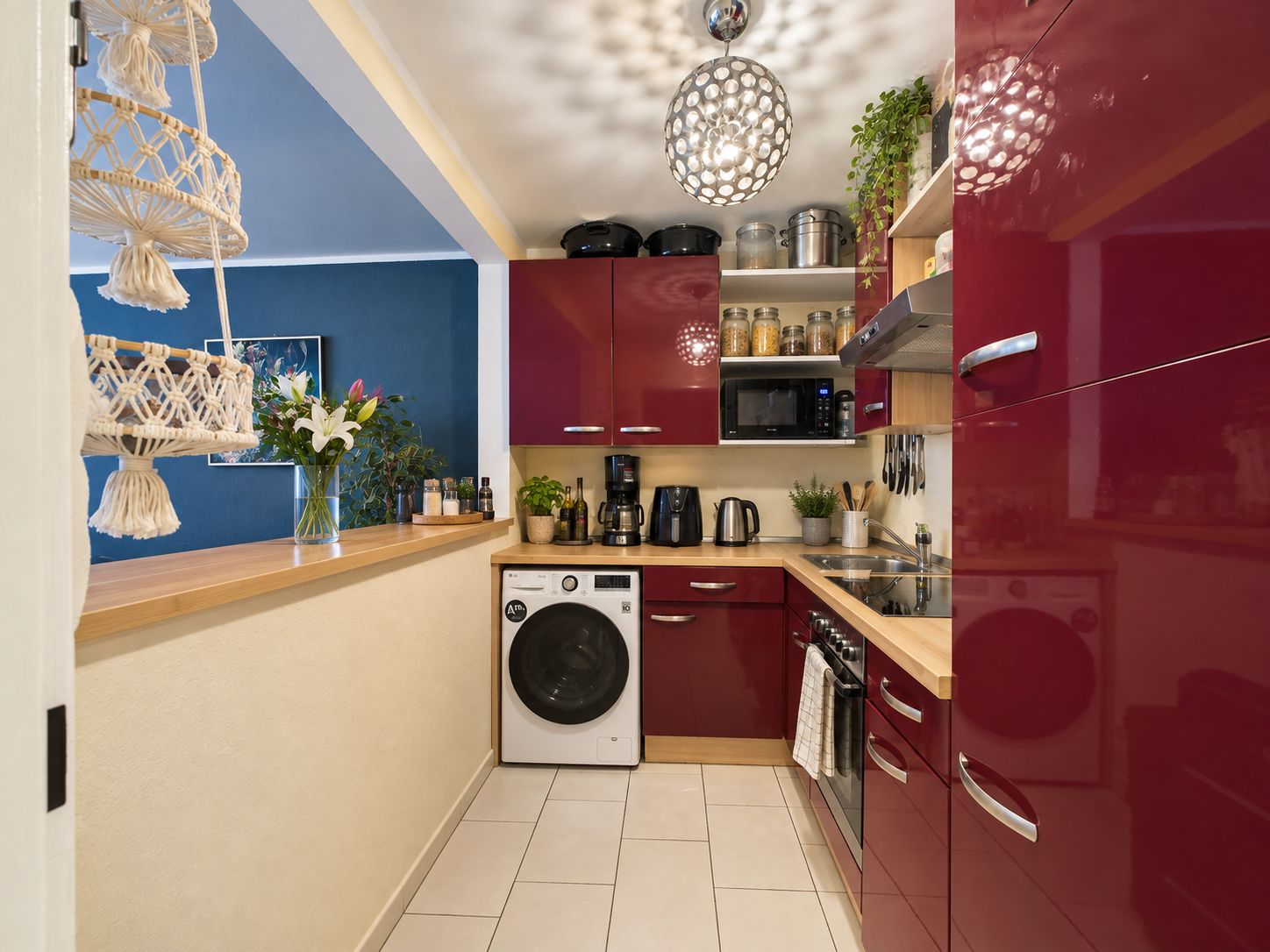 Moderne Küche mit roten Hochglanzschränken, Holzarbeitsplatten und Waschmaschine.