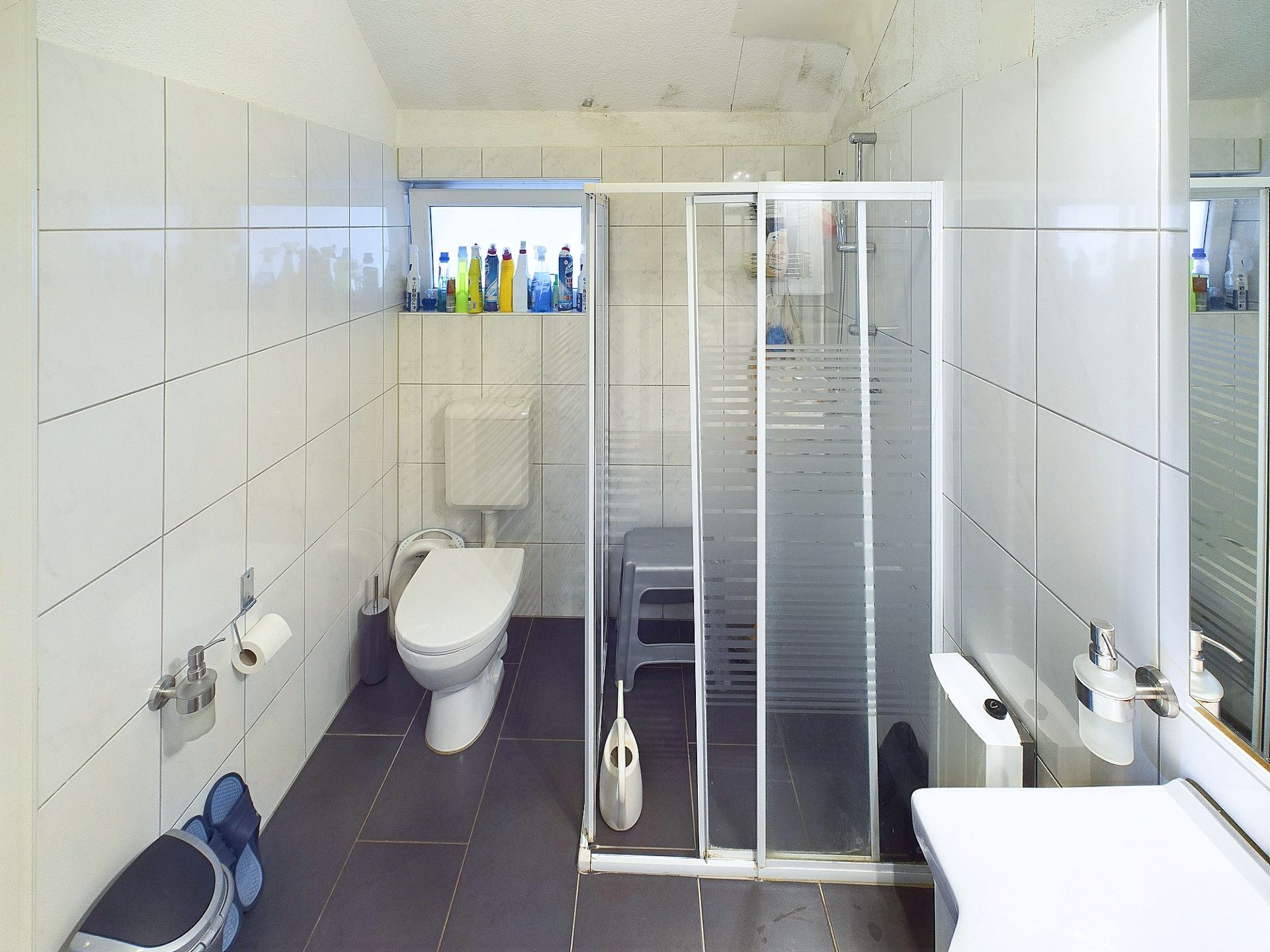 Modernes Badezimmer mit Toilette, Dusche, Waschbecken und kleinen Fenstern.
