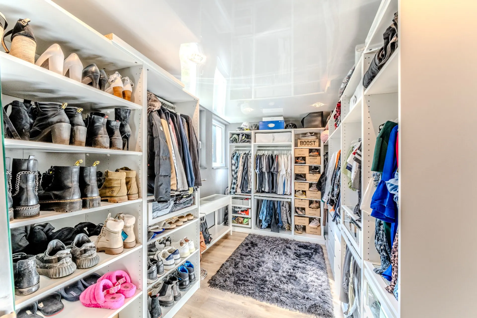 Heller begehbarer Kleiderschrank mit Regalen für Schuhe, Kleidung und Accessoires.