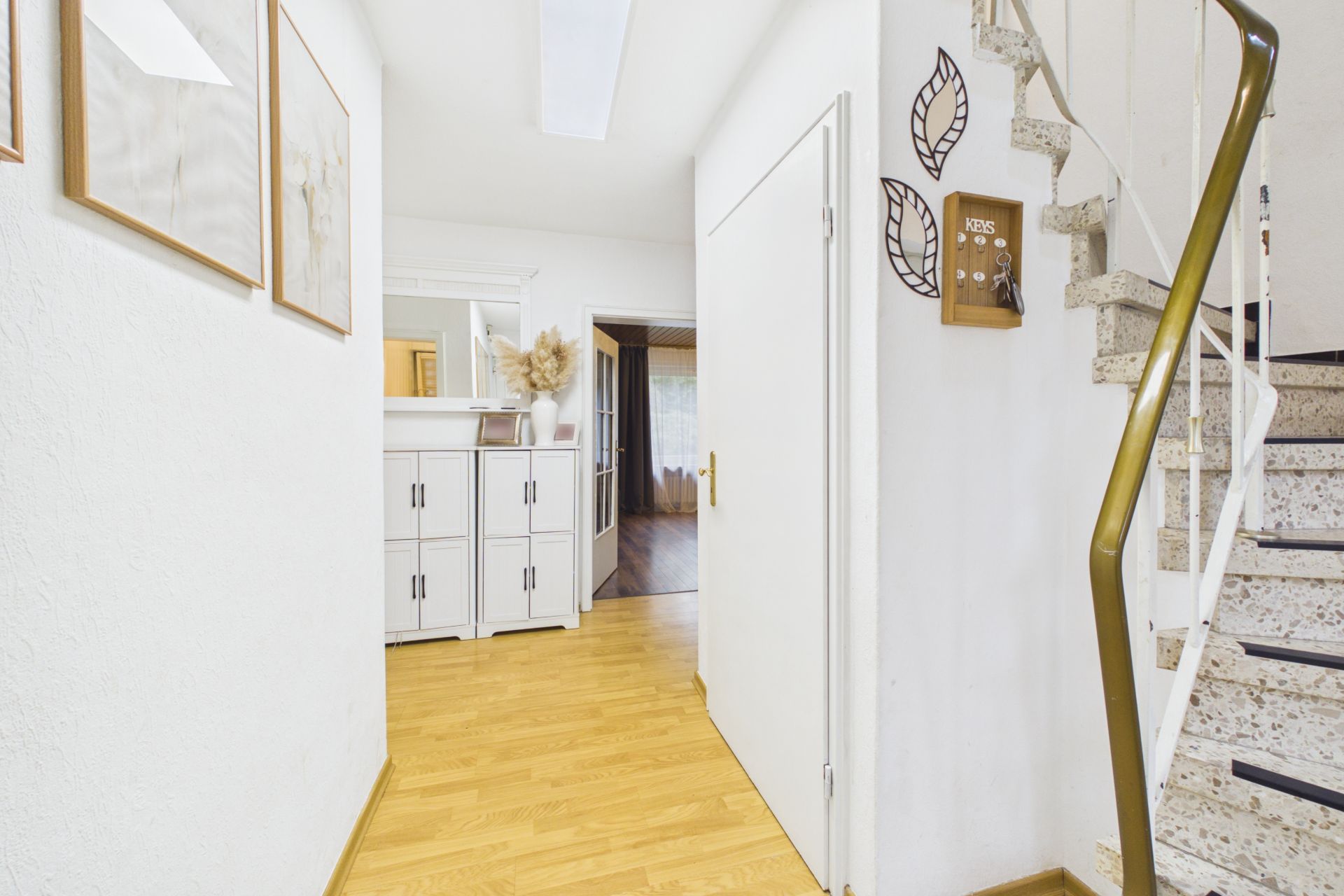 Heller Flur mit Holzfußboden, weißem Schrank und Treppe im Wohnhaus.