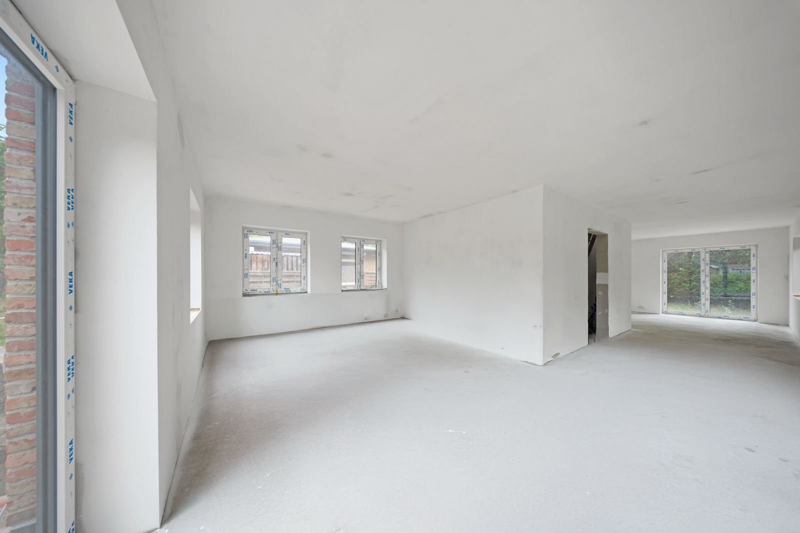 Heller, leerer Raum mit weißen Wänden und mehreren Fenstern in einem Wohnhaus.