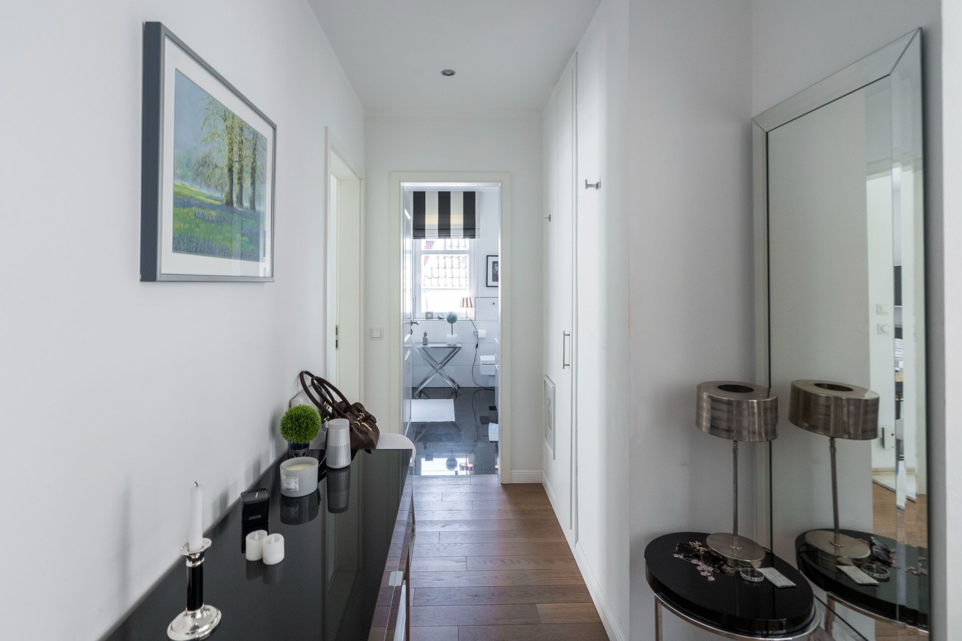 Heller Flur mit Spiegel, Schränken, Dekoration und Blick in ein Badezimmer.