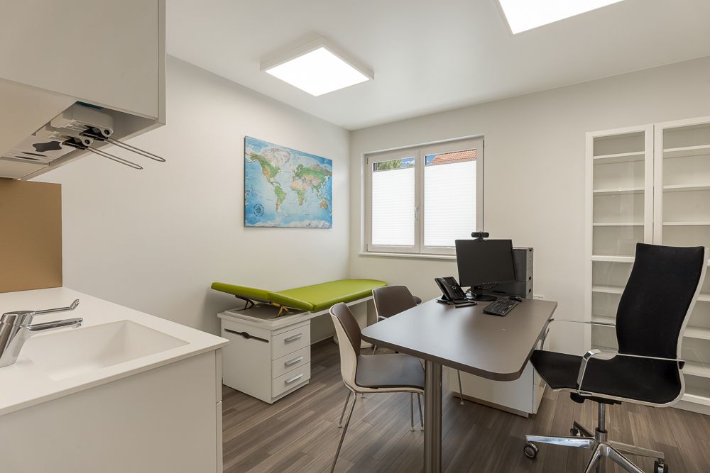 Modernes, helles Arbeitszimmer mit Schreibtisch, Bürostuhl, Weltkarte und Fenster.