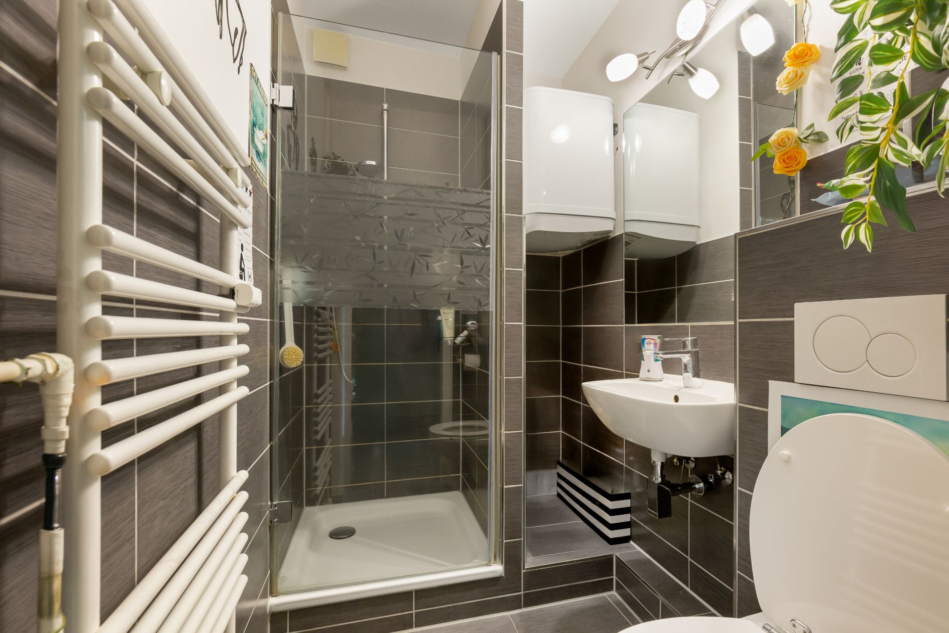 Modernes kleines Badezimmer mit Dusche, Waschbecken, Toilette und Wandspiegel.