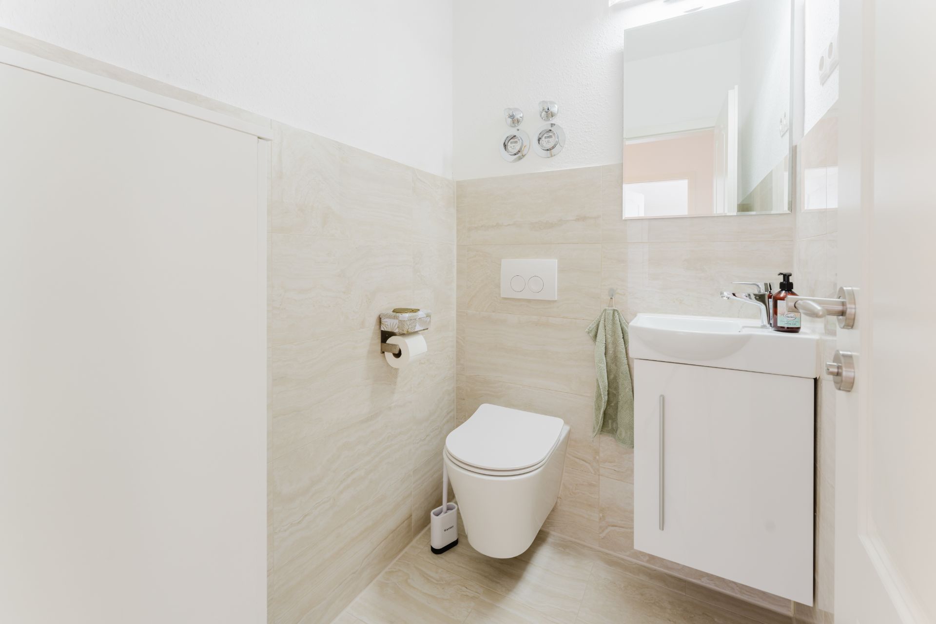 Modernes, helles Badezimmer mit WC, Waschbecken und Spiegel.