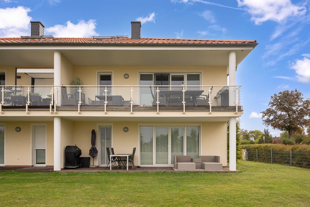 Modernes zweistöckiges Wohnhaus mit Balkon und Gartenmöbeln auf der Terrasse.