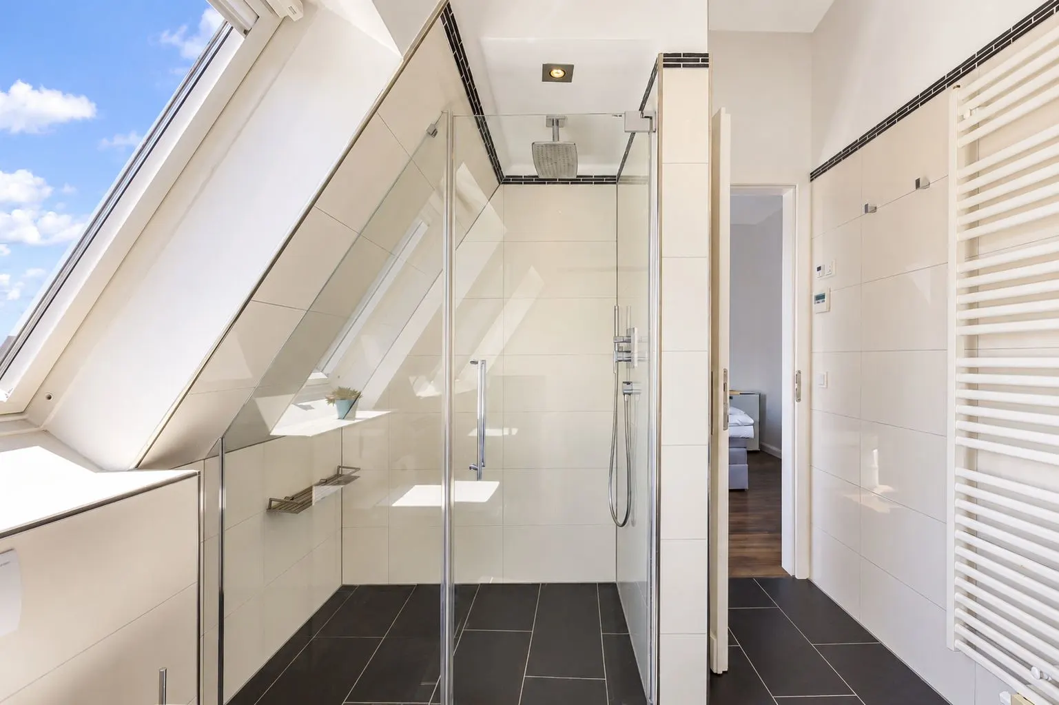 Modernes Badezimmer mit Glasdusche, Dachfenster und Wandheizkörper.