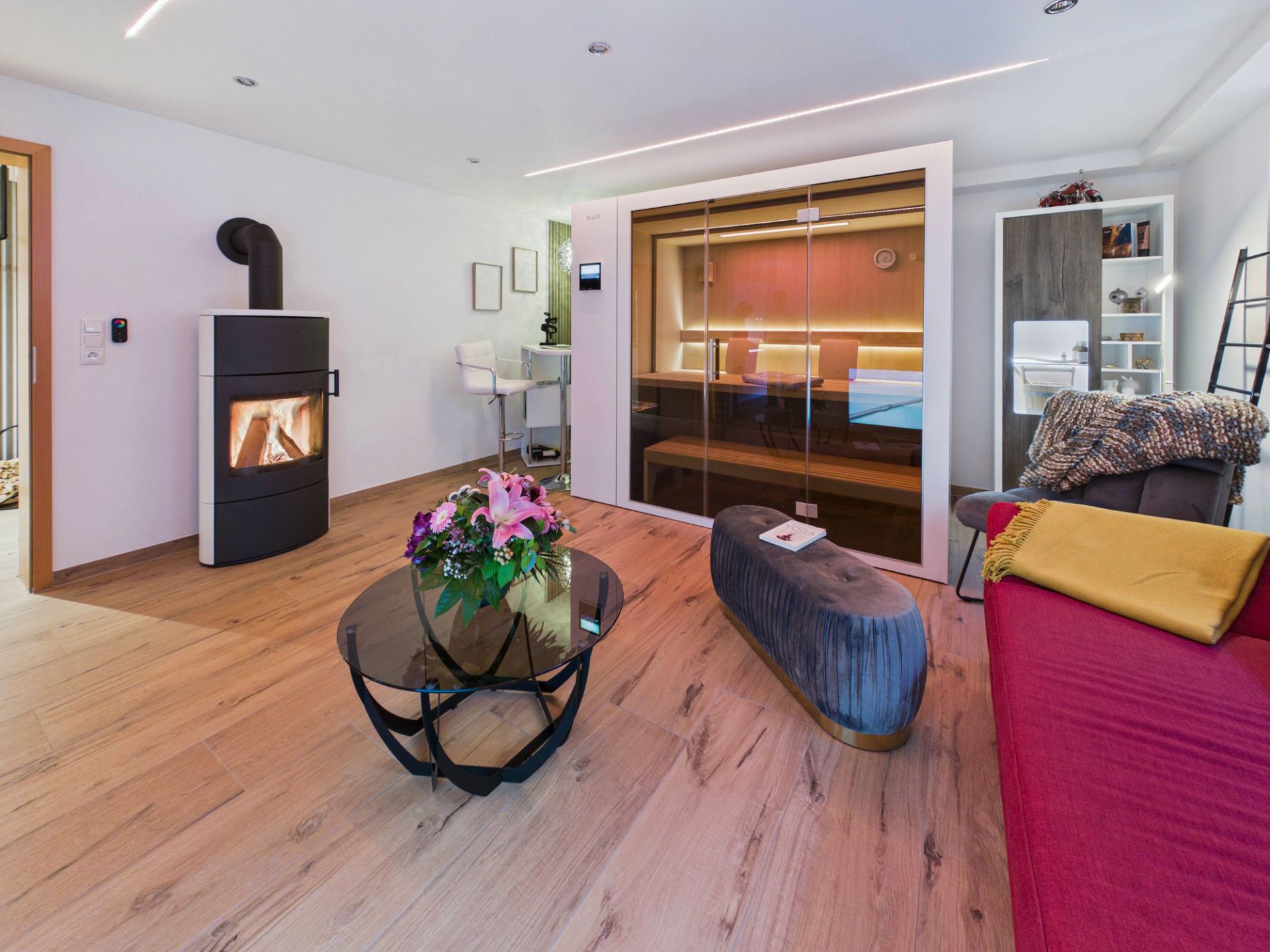 Modernes Wohnzimmer mit Kamin, Glas-Couchtisch, Sauna und rotem Sofa.