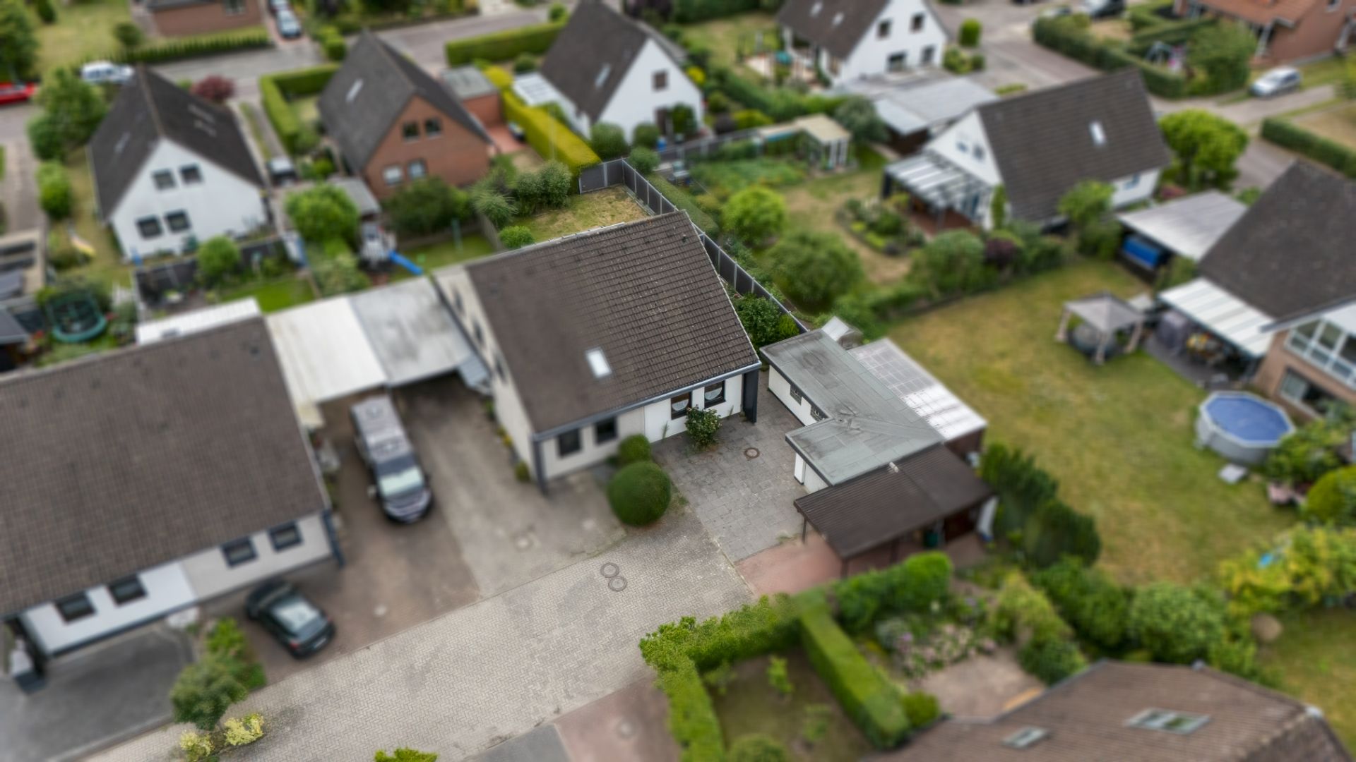 Luftaufnahme eines Wohnhauses mit Garten und Nachbargrundstücken in einer Siedlung.