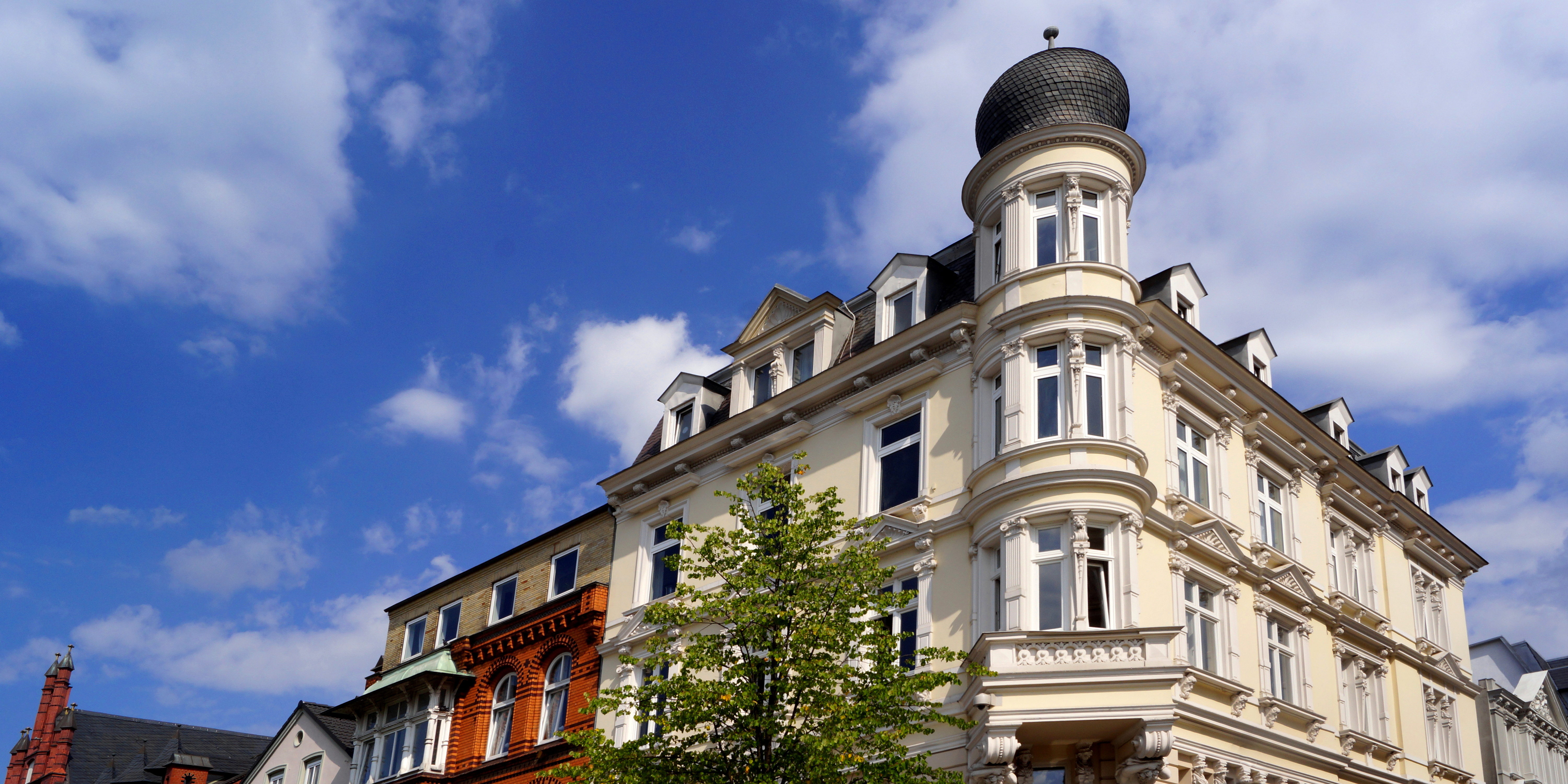 See mit Bäumen und modernen Gebäuden am Ufer unter blauem Himmel.