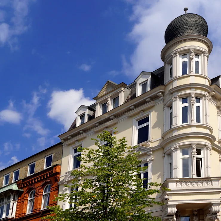 See mit Bäumen und modernen Gebäuden am Ufer unter blauem Himmel.