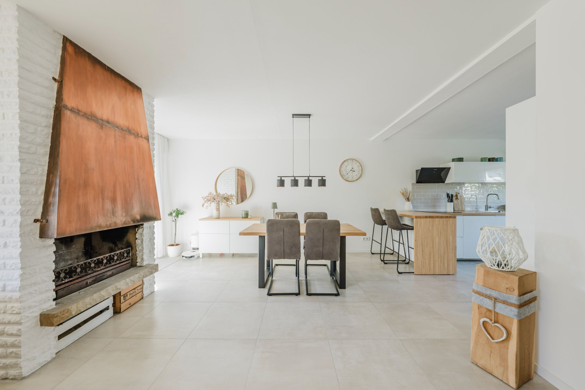 Helles Wohnzimmer mit Kamin, Esstisch und offener Küche, modern eingerichtet.