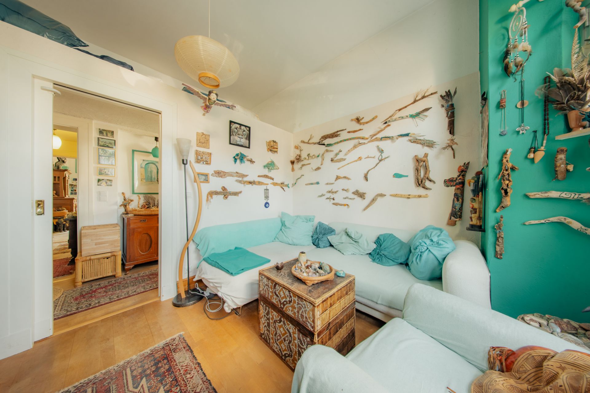 Helles Wohnzimmer mit weißem Sofa, Holzboden und Deko aus Treibholz an den Wänden.