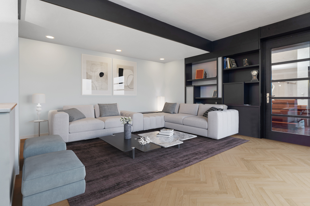 Modernes Wohnzimmer mit grauem Sofa, Couchtisch und Regalwand auf hellem Holzboden.