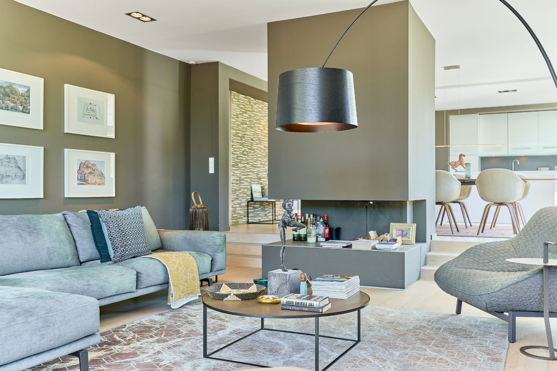 Modernes Wohnzimmer mit Sofa, Couchtisch, Kamin und Blick auf offene Küche.