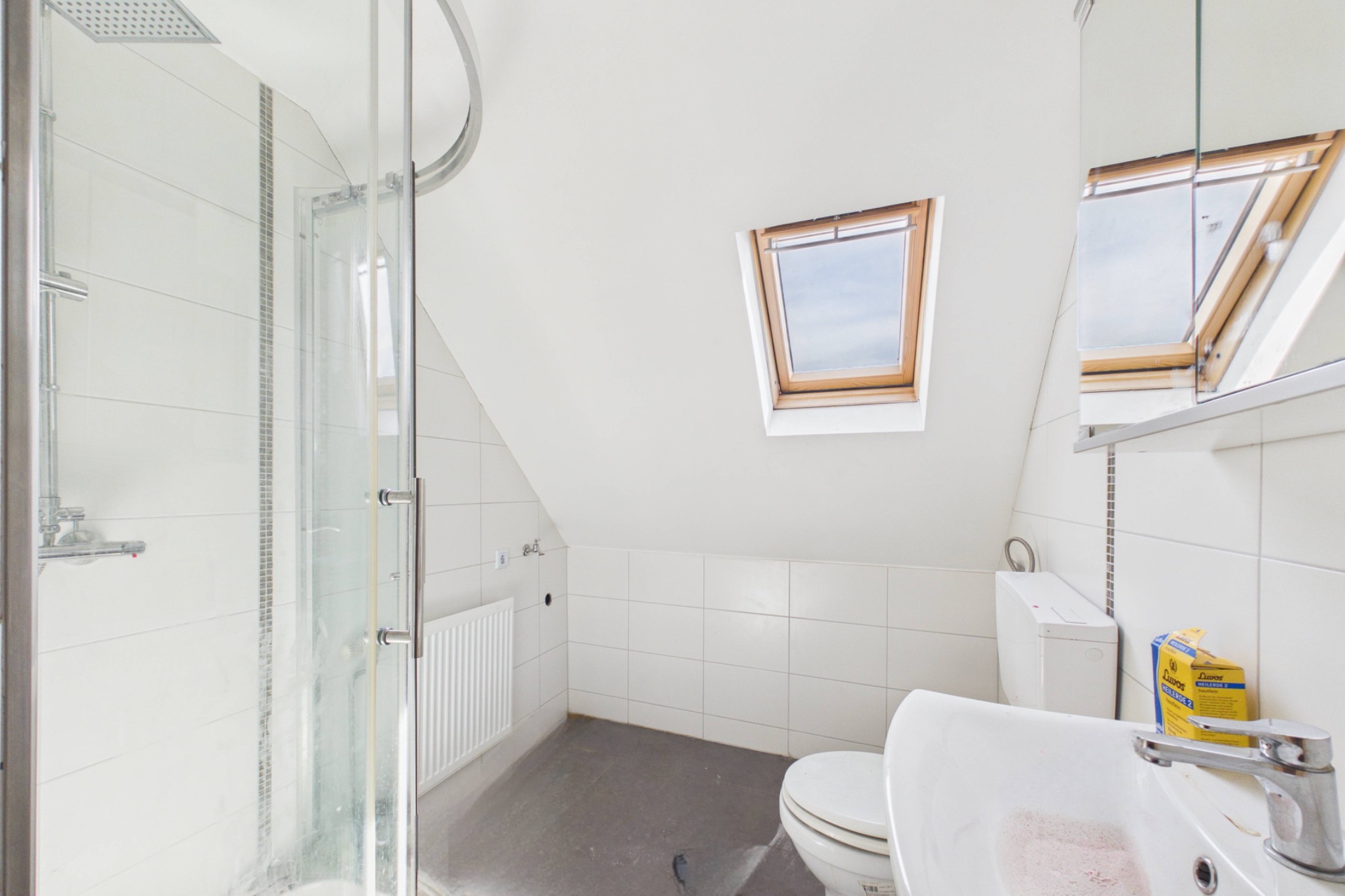 Helles Badezimmer mit Dusche, WC, Waschbecken und zwei Dachfenstern.