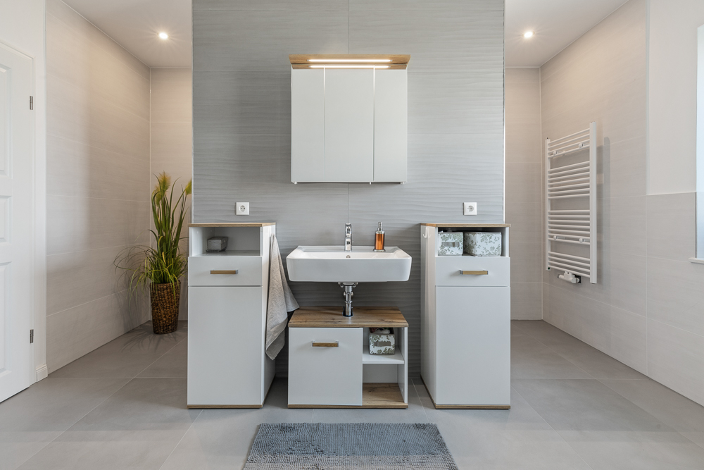Modernes Badezimmer mit weißem Waschbecken, Schrank, Handtuch und einem Pflanzkorb.