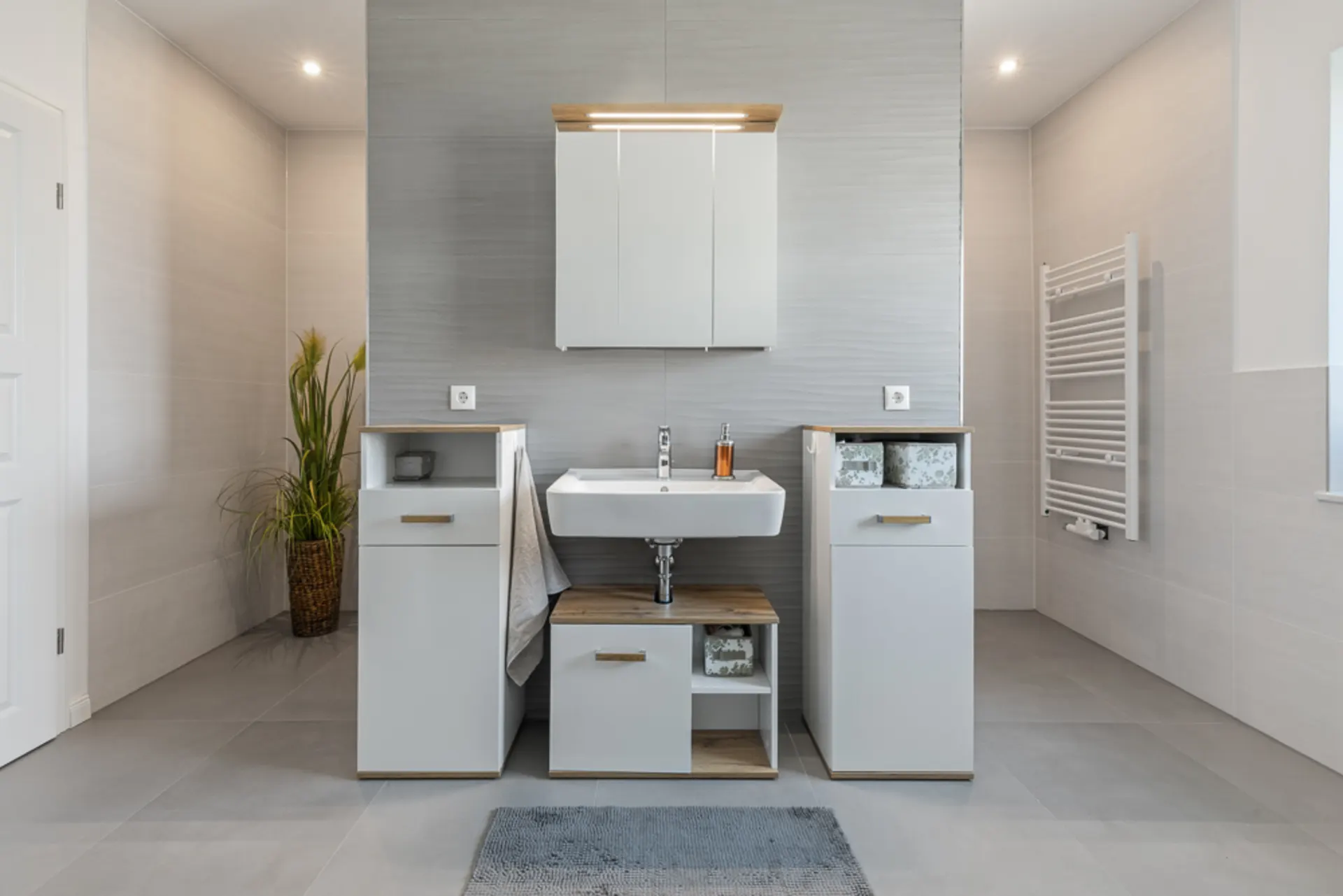 Modernes Badezimmer mit weißem Waschbecken, Schrank, Handtuch und einem Pflanzkorb.