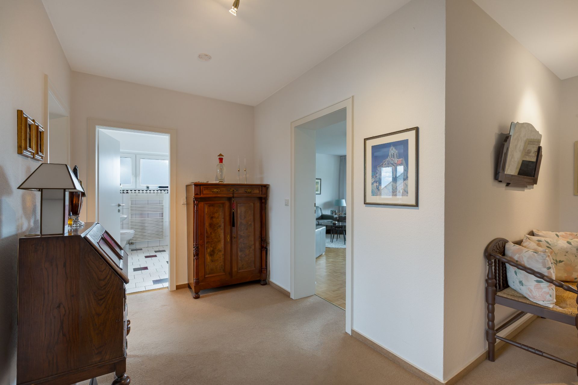 Heller Flur mit Holzmöbeln, Blick ins Wohnzimmer und Badezimmer.