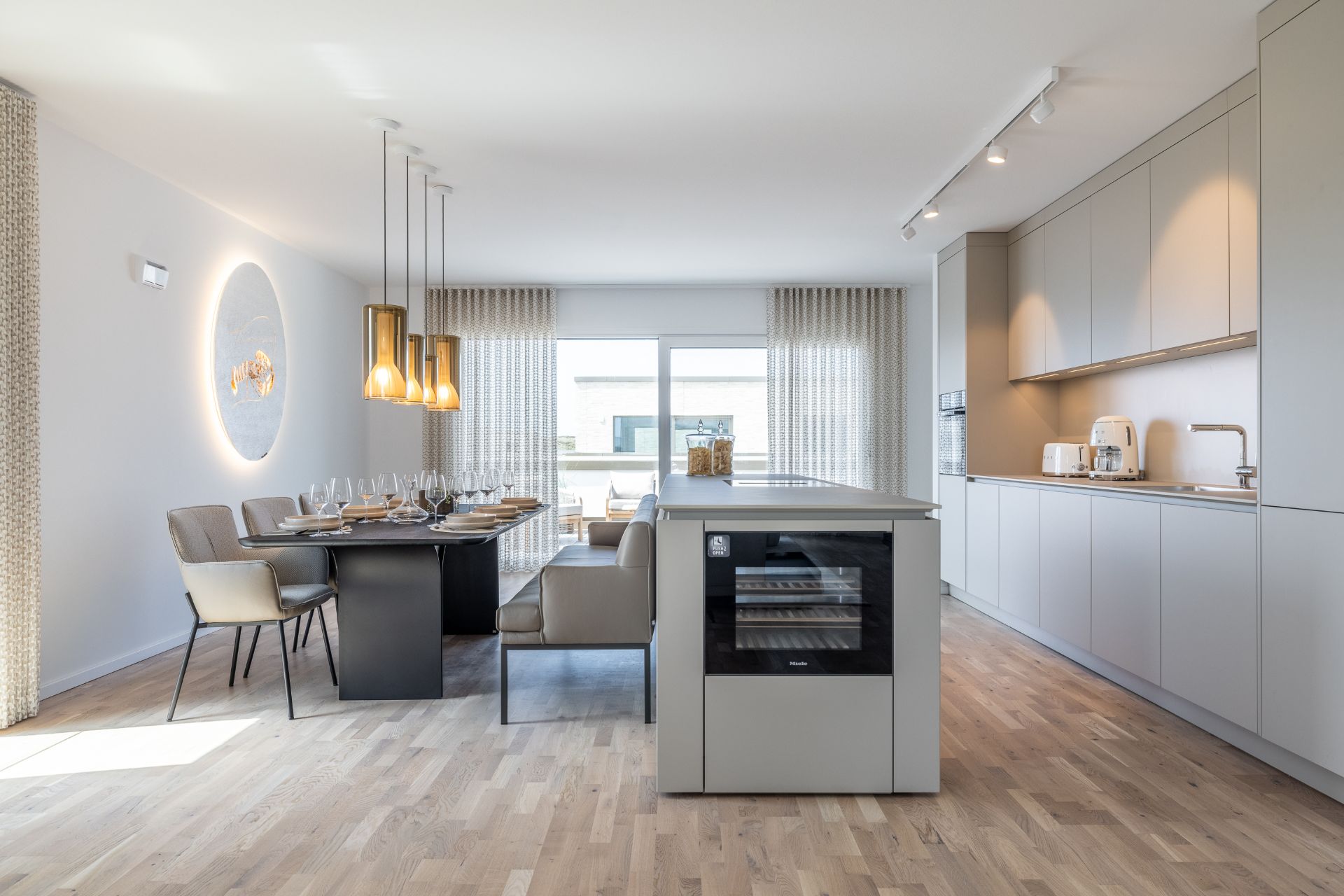 Helle, moderne Küche mit Esstisch, Stühlen und bodentiefen Fenstern.