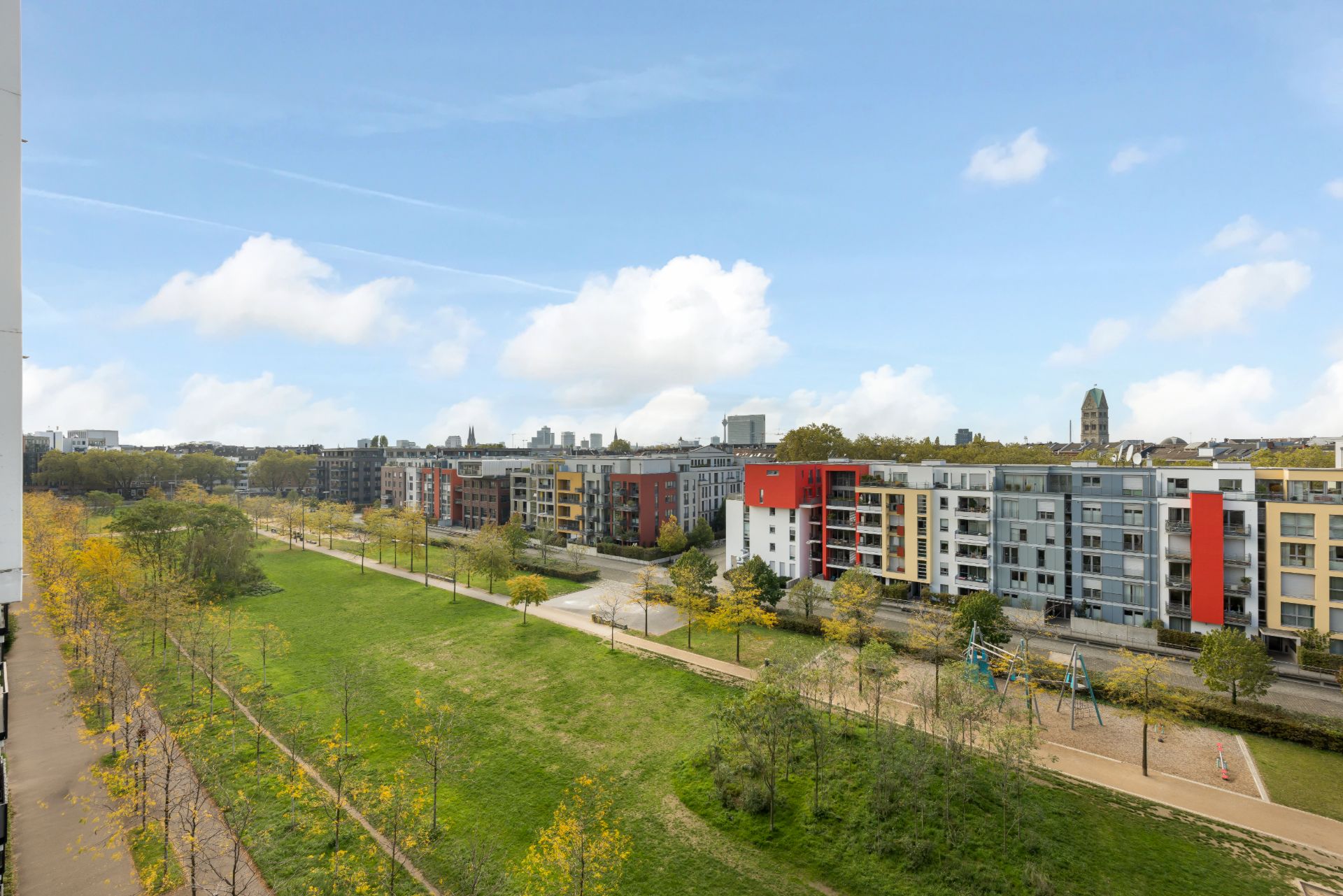 Blick auf moderne Wohngebäude mit Parkanlage und Spielplatz im Vordergrund.