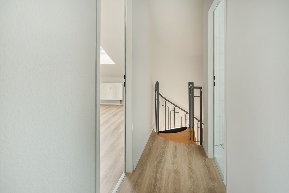 Flur mit Holzfußboden, einer Wendeltreppe und Türen zu weiteren Räumen.