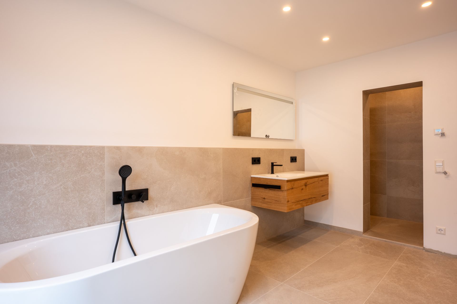 Modernes Badezimmer mit freistehender Badewanne, Waschbecken, Spiegel und begehbarer Dusche.