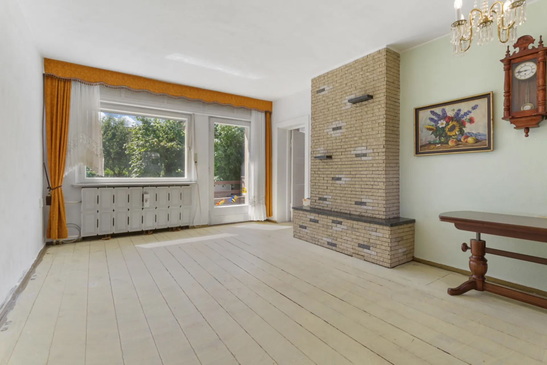 Helles Wohnzimmer mit großem Fenster, gelben Vorhängen, Kamin, Uhr und Bild an der Wand.