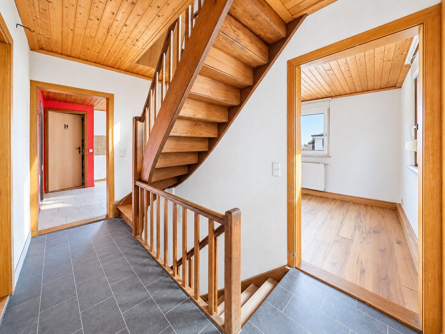 Flur mit Holztreppe, Türen zu angrenzenden Zimmern, Holzboden und Holzdecke.