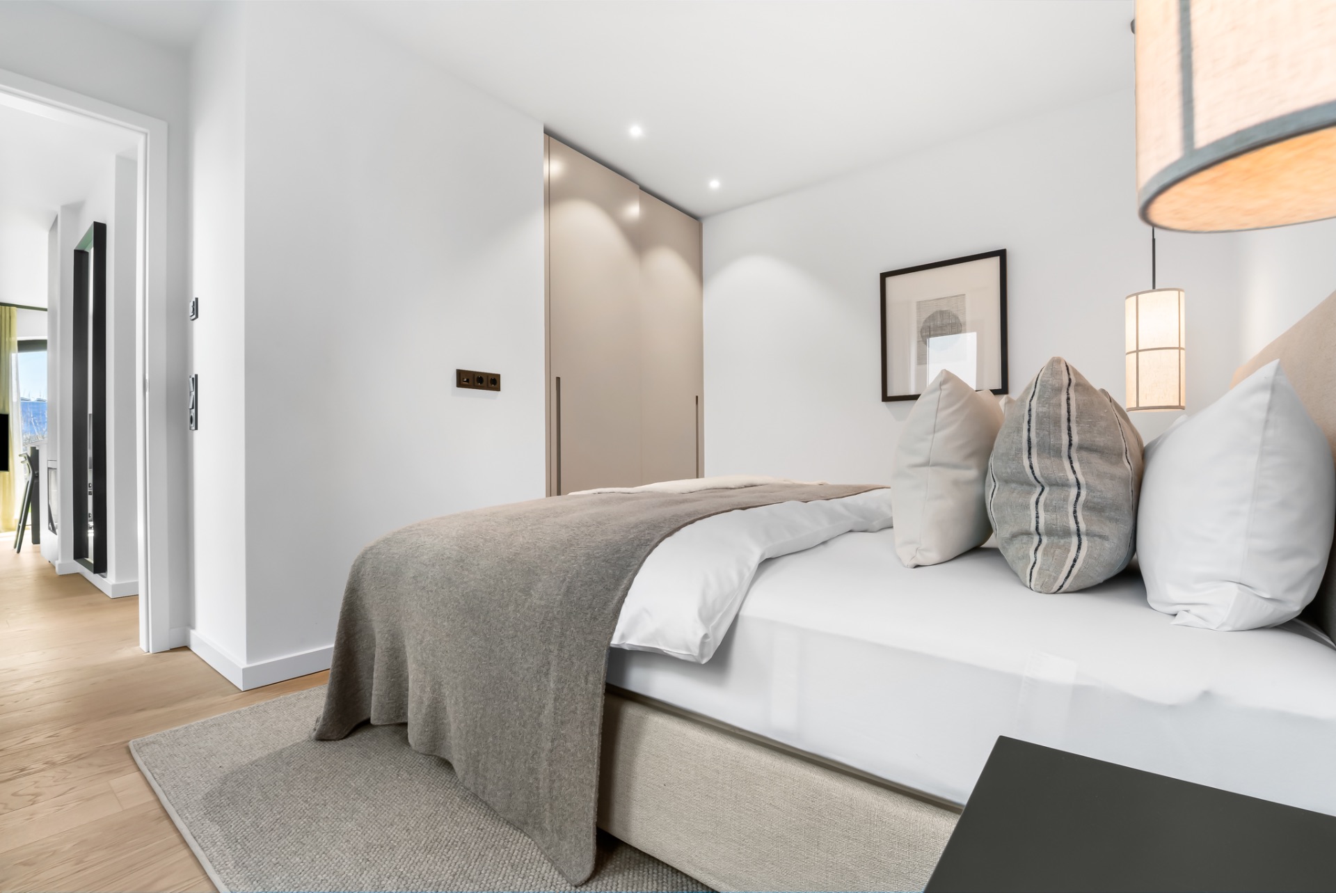 Modernes Schlafzimmer mit großem Bett, grauer Decke und Einbauschrank.