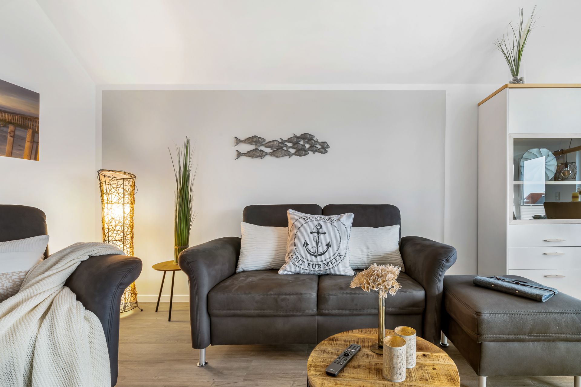 Wohnzimmer mit braunem Sofa, Kissen, Holz-Couchtisch und Dekoration an der Wand.