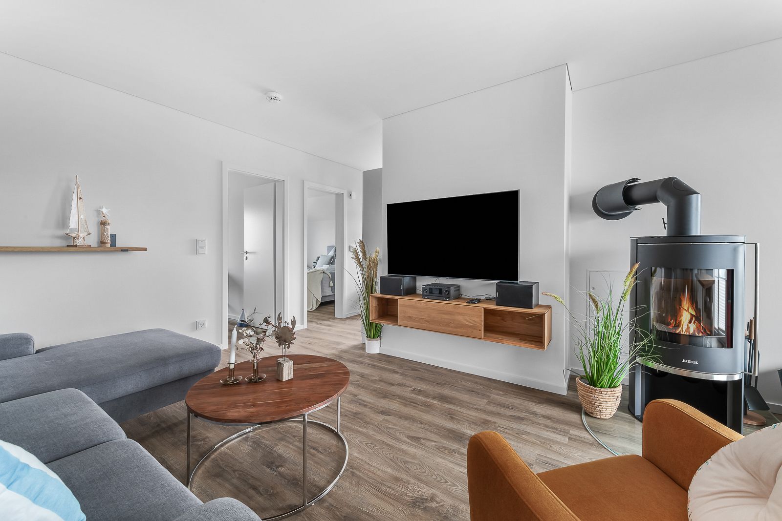 Modernes Wohnzimmer mit Sofa, Fernseher, Kamin, Holztisch und Pflanzen.