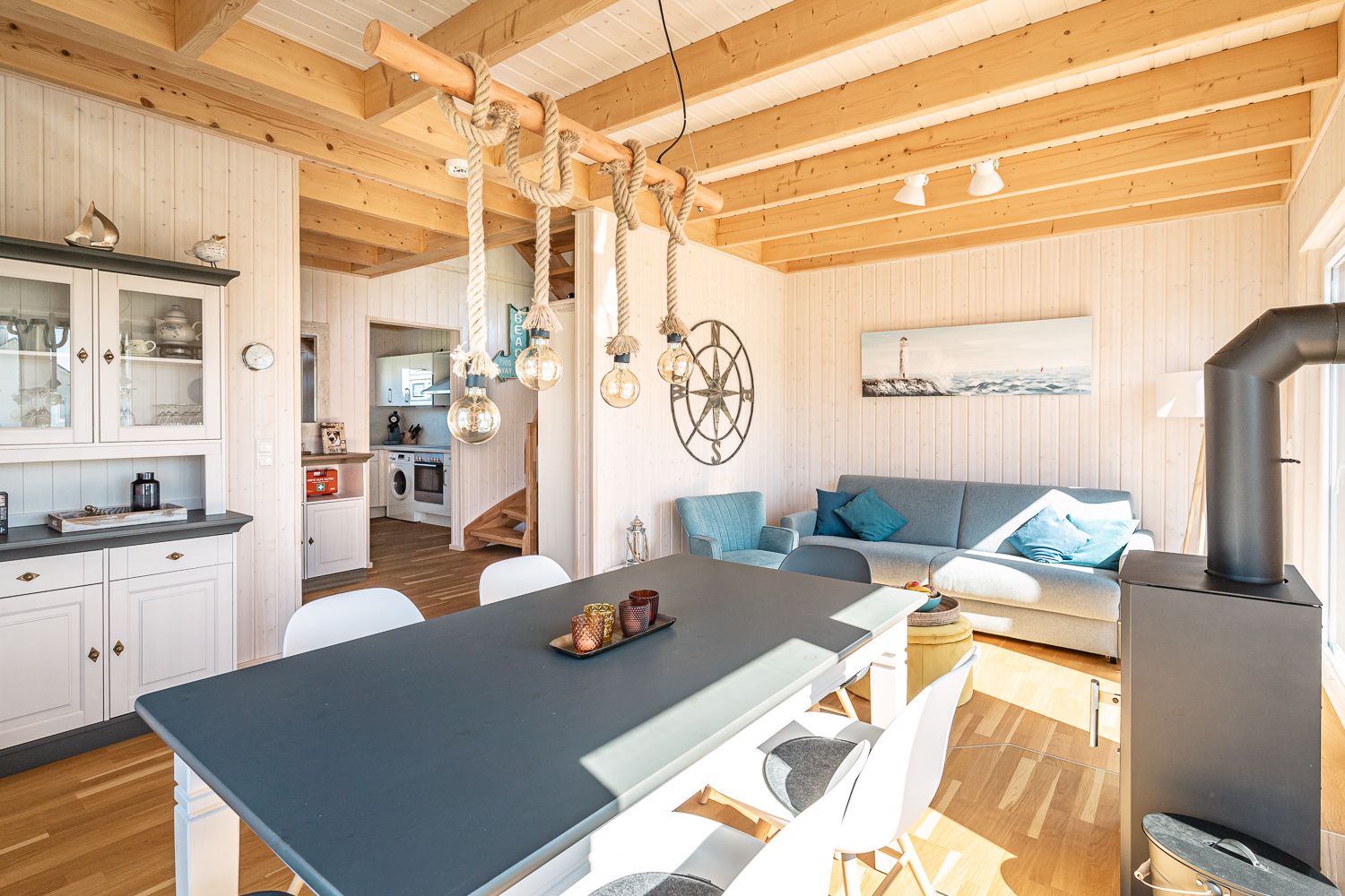 Heller Wohn- und Essbereich mit Holzbalkendecke, Esstisch, Sofa und Kamin.