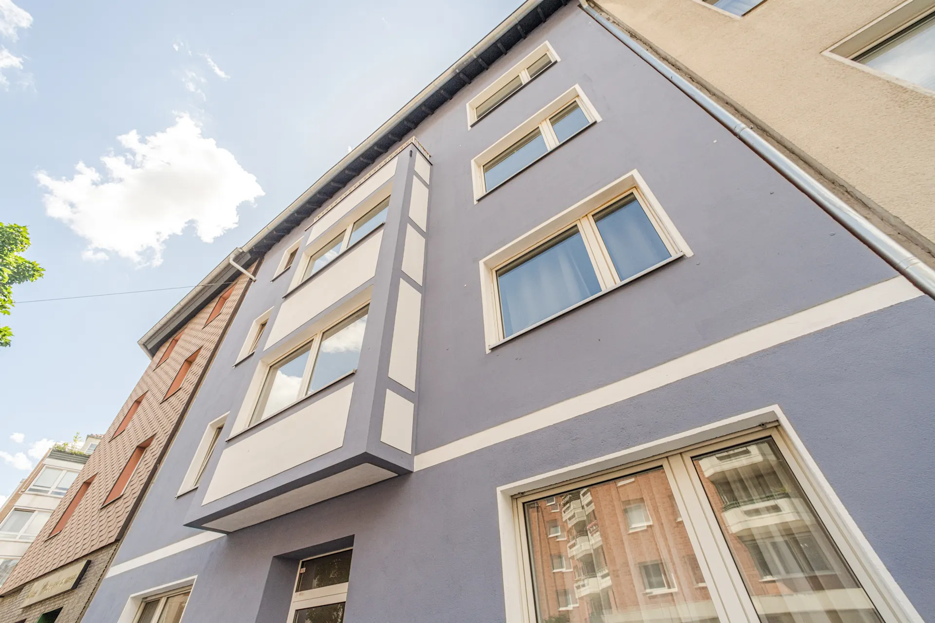 Fassade eines mehrstöckigen Wohnhauses mit blauer und weißer Farbe und mehreren Fenstern.