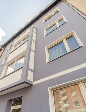 Fassade eines mehrstöckigen Wohnhauses mit blauer und weißer Farbe und mehreren Fenstern.