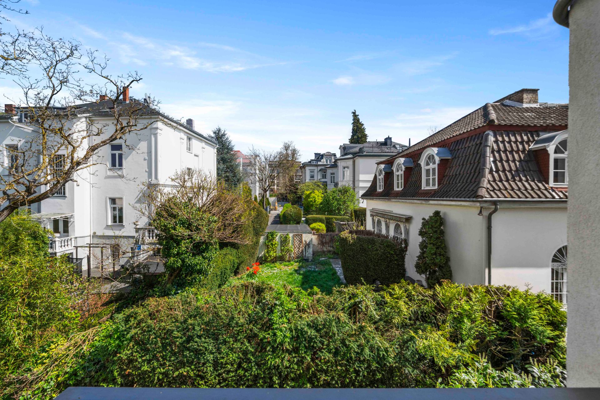 Blick auf gepflegten Garten mit Hecken, umgeben von weißen Wohnhäusern.