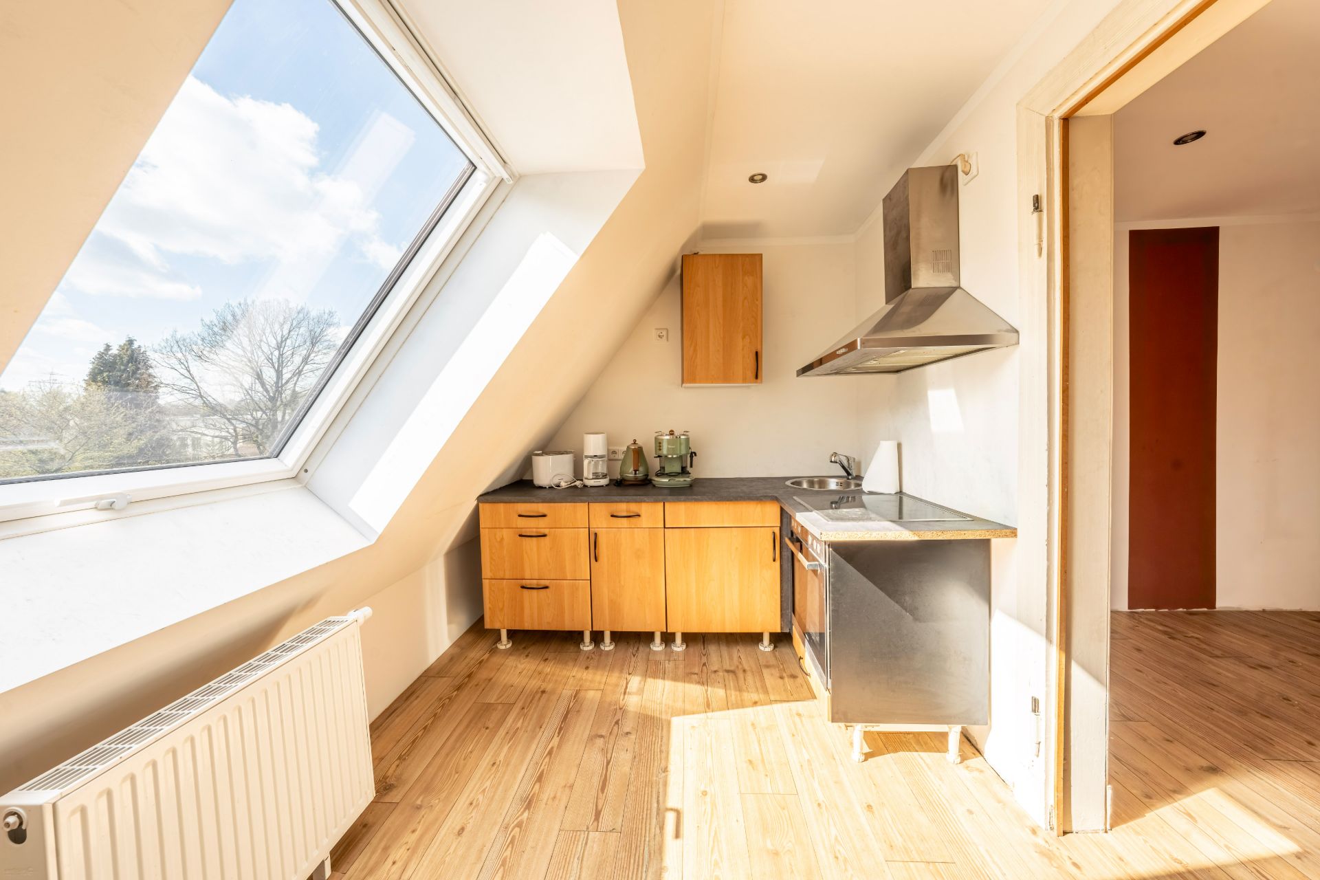 Helle Küche mit Dachfenster, Holzfußboden und modernen Geräten.