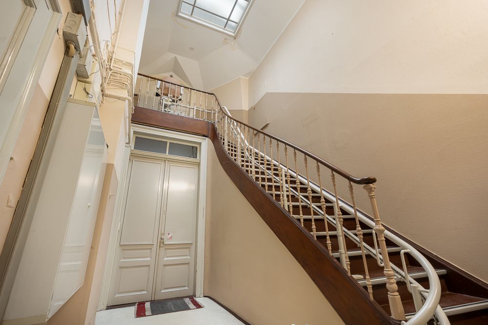Treppenhaus mit Holzgeländer und Doppeltür, Oberlicht an der Decke.