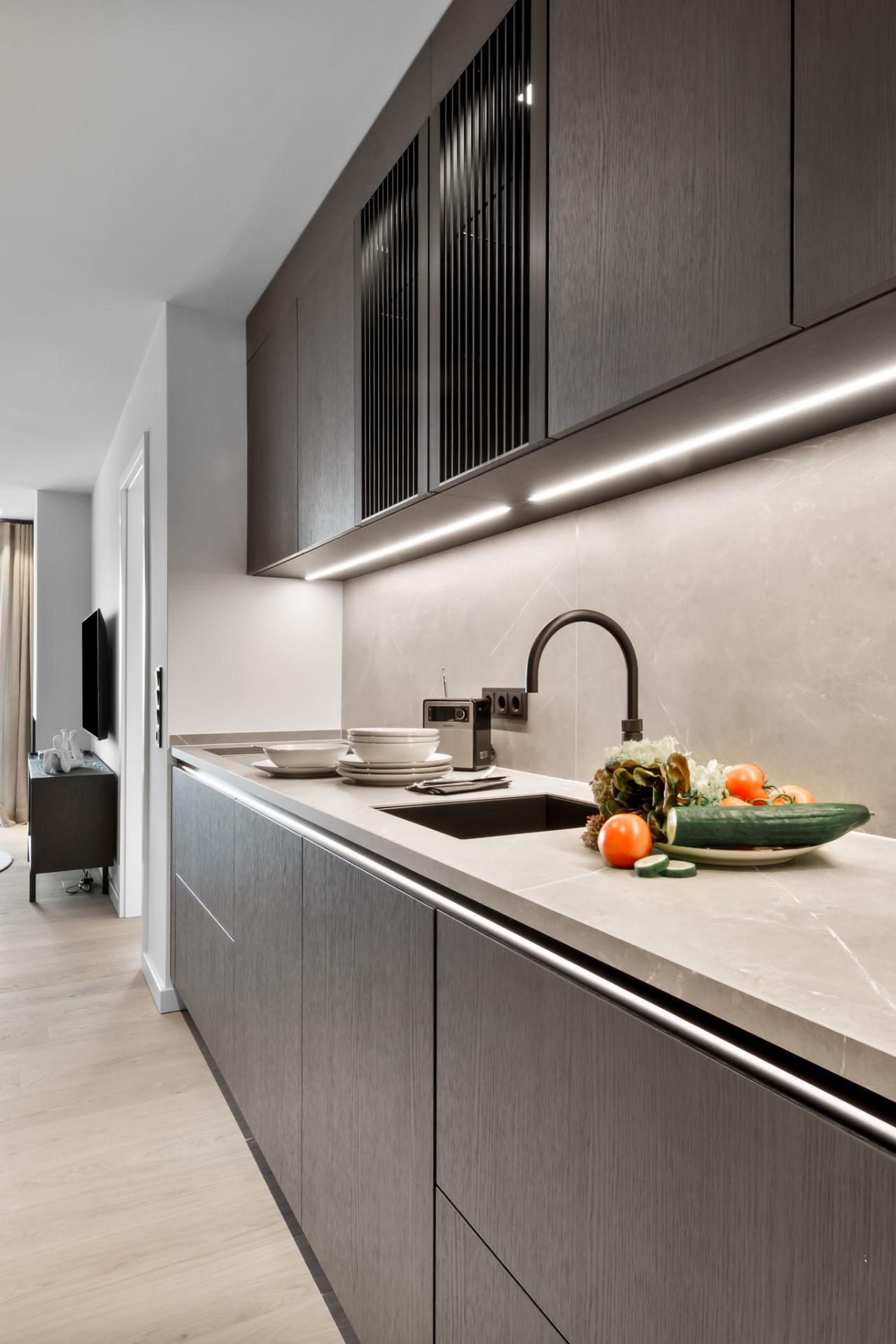 Moderne Küche mit dunklen Schränken, Spüle und Gemüse auf der Arbeitsplatte.