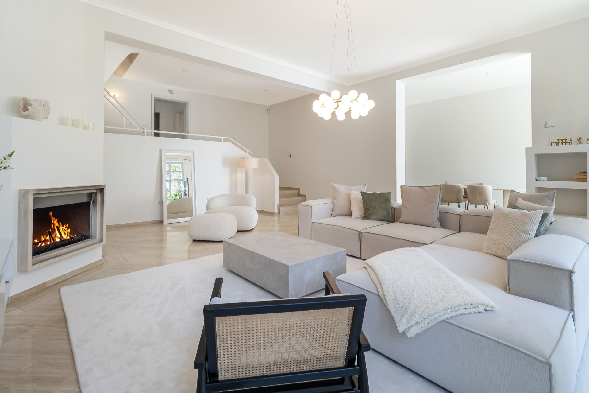Modernes Wohnzimmer mit Kamin, hellem Sofa, Couchtisch und beigem Teppich.