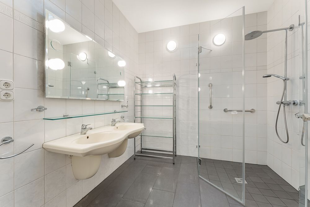 Modernes Badezimmer mit zwei Waschbecken, großer Spiegelwand und ebenerdiger Dusche.
