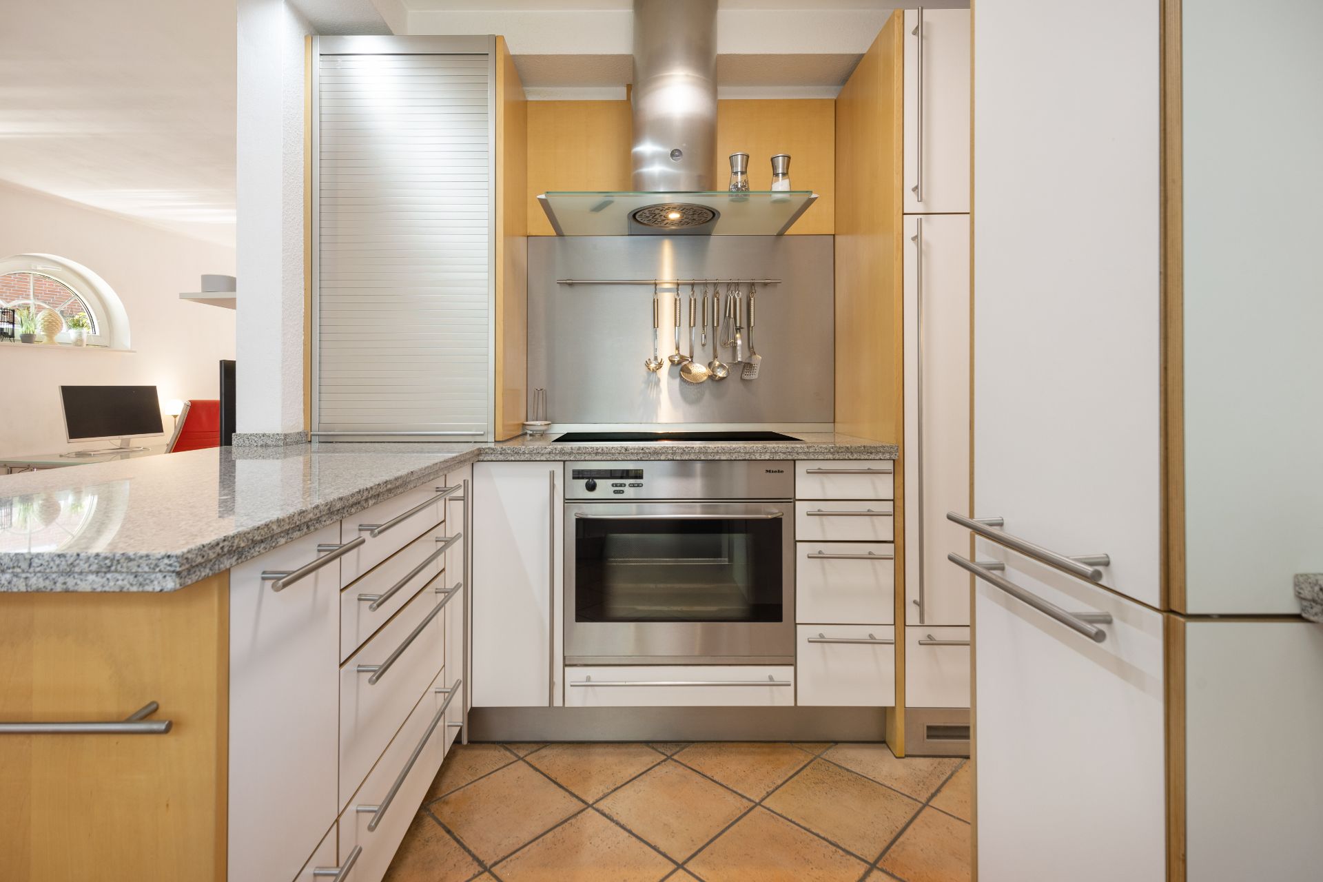 Moderne Einbauküche mit Herd, Backofen, Dunstabzugshaube und Hängeschränken.