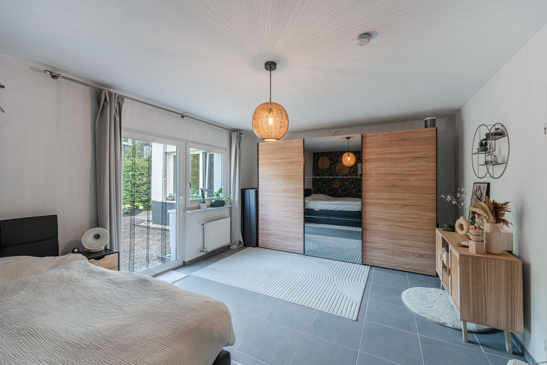 Modernes Schlafzimmer mit Doppelbett, großem Kleiderschrank und Zugang zur Terrasse.