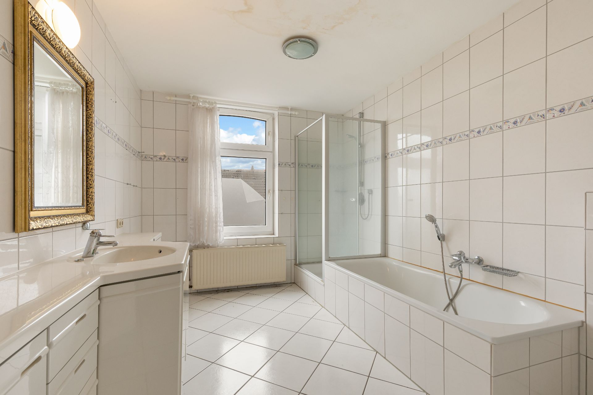 Helles Badezimmer mit Badewanne, Dusche, Waschbecken und Fenster.