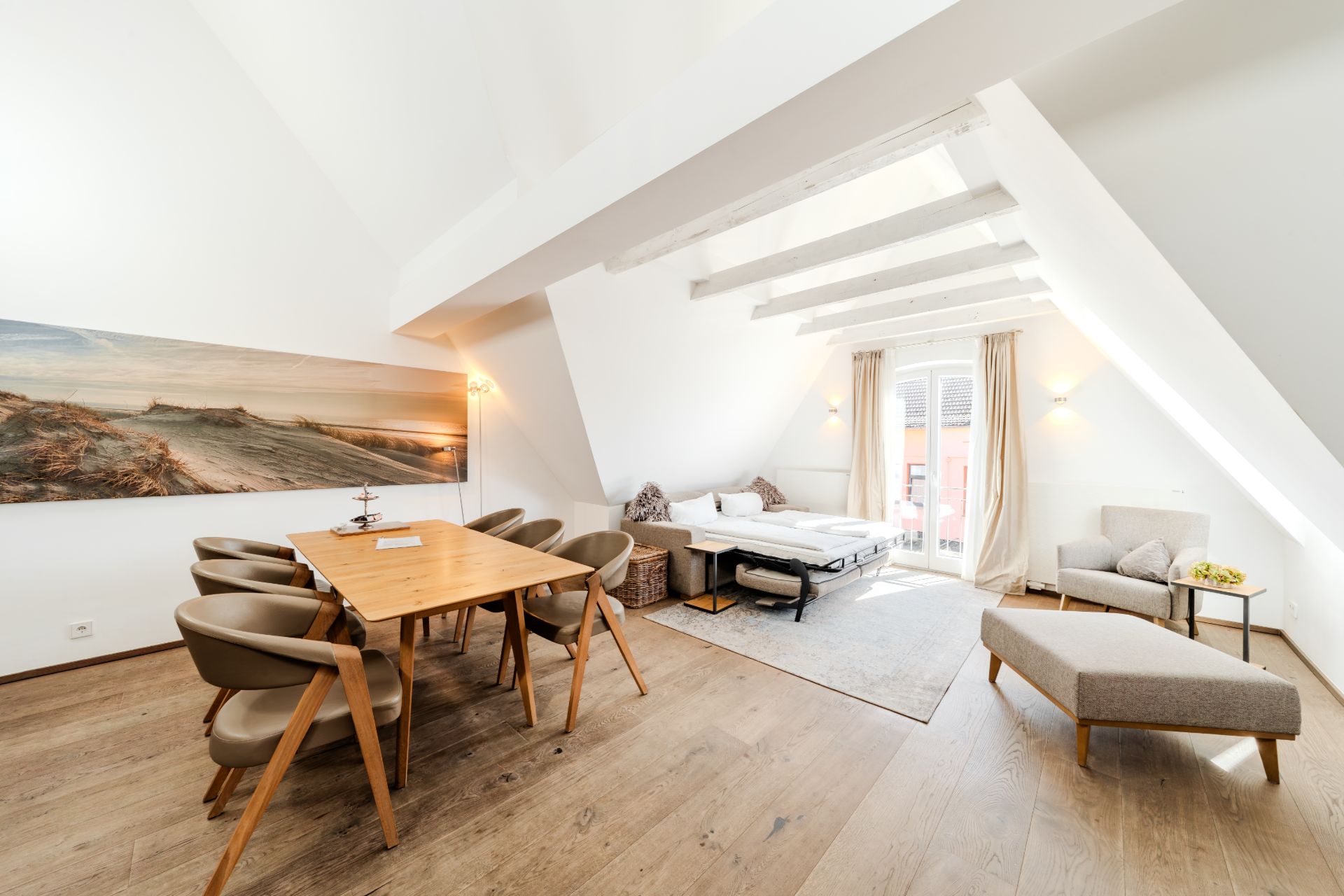 Helles Wohn- und Esszimmer mit Esstisch, Stühlen, Sofa, Sessel und großem Fenster.