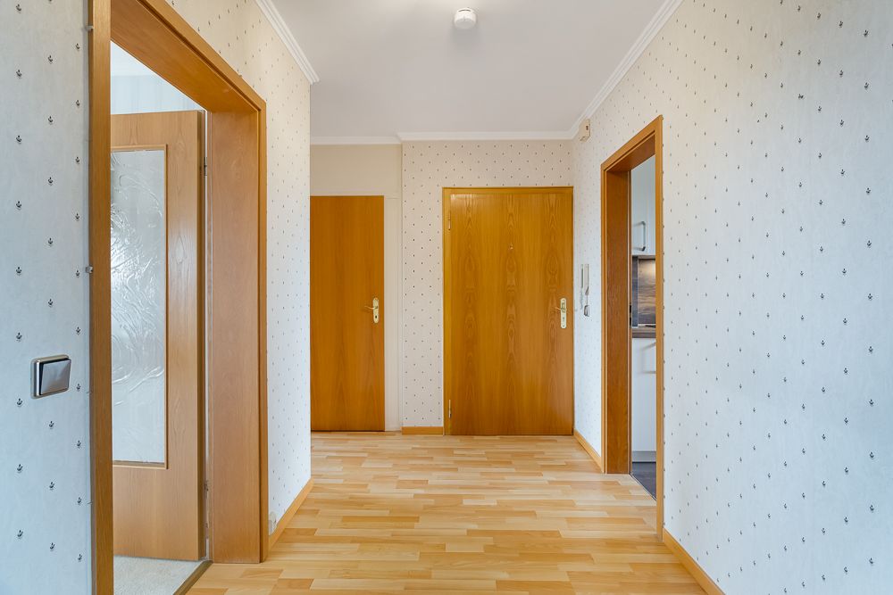 Heller Flur mit Holztüren, hellem Laminatboden und hell gemusterten Wänden.
