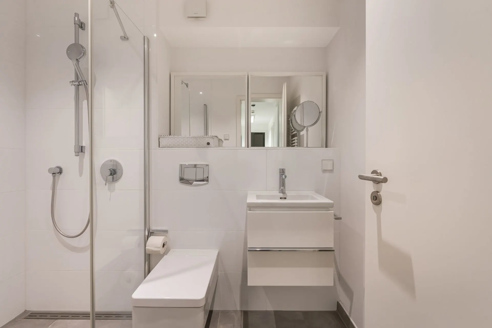 Modernes Badezimmer mit Dusche, Toilette, Waschbecken und großem Spiegel.