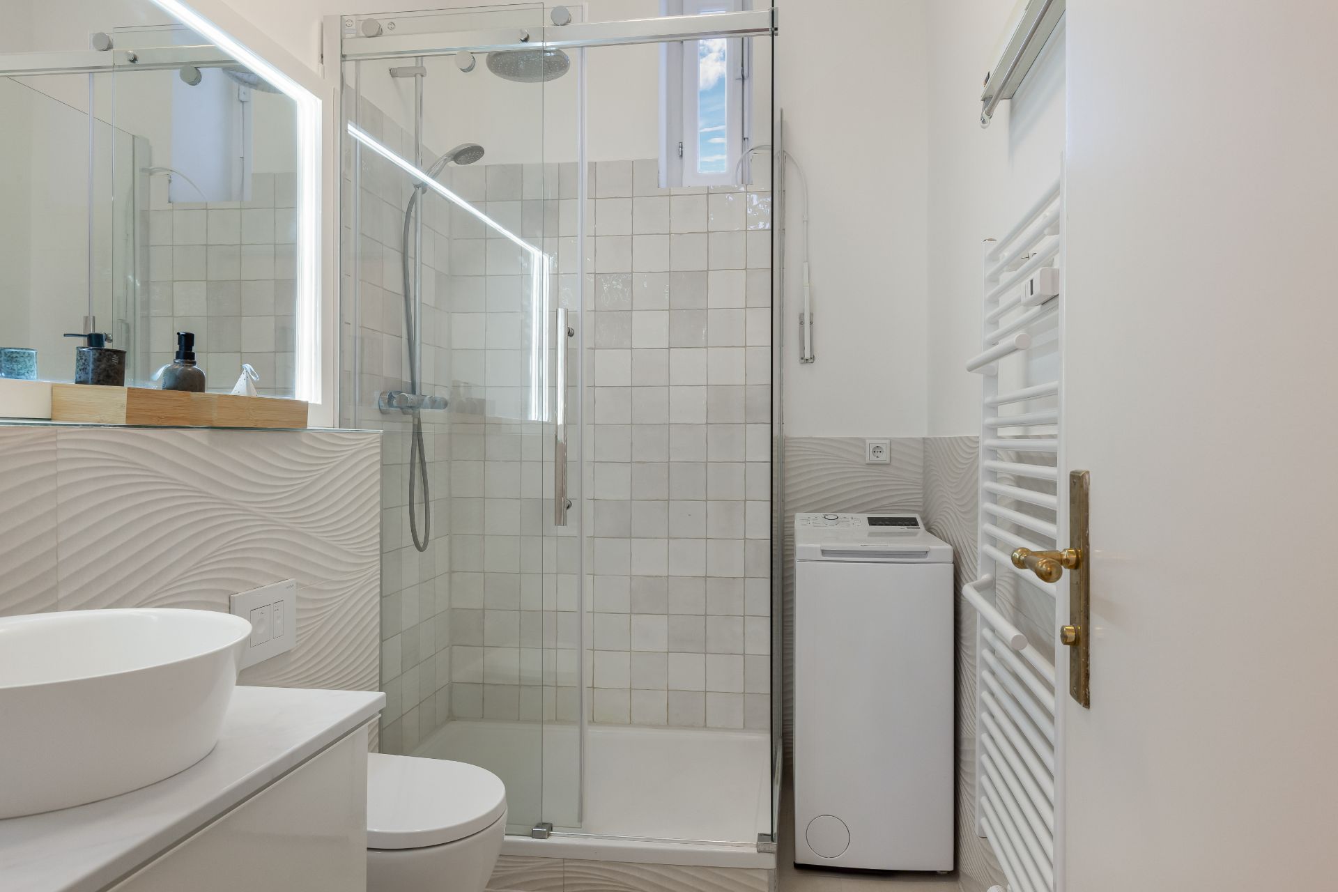 Modernes Badezimmer mit Dusche, Waschbecken, WC und Waschmaschine.